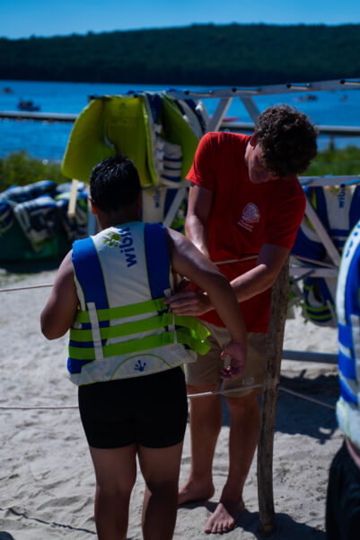 Moniteur équipant un enfant d'un gilet avant d'aller sur le Wi Splash au lac des Vieilles Forges