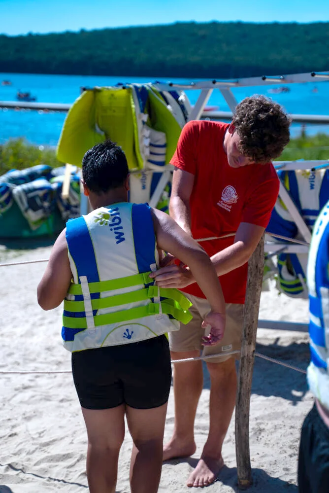 Moniteur équipant un enfant d'un gilet avant d'aller sur le Wisplash
